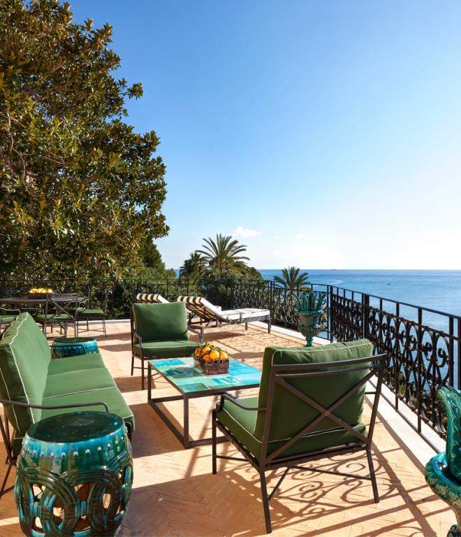 Terrasse der Villa Igiea mit grünen Sitzmöbeln, einem türkisen Tisch und Blick auf den Golf von Palermo
