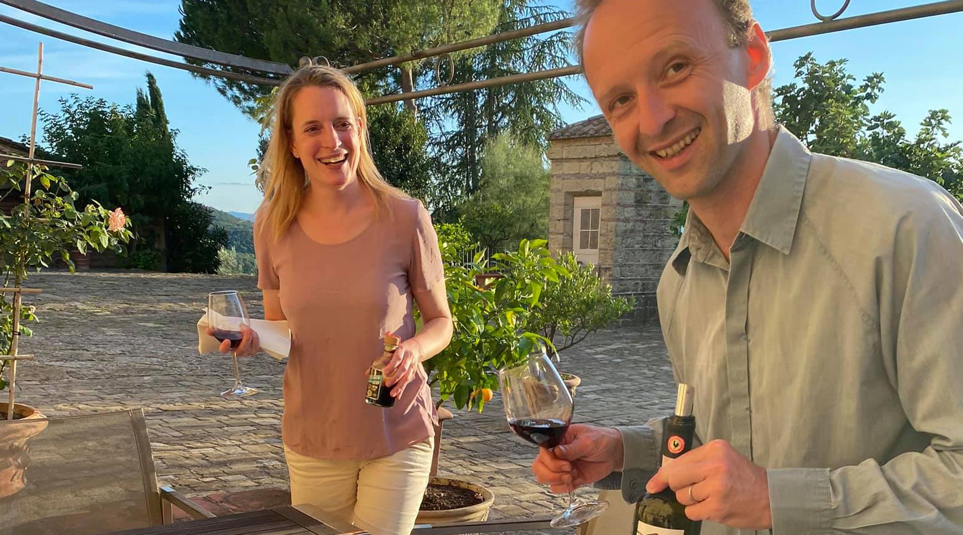Eine Frau und ein Mann mit Weingläsern in der Hand auf einer steinernen Terrasse