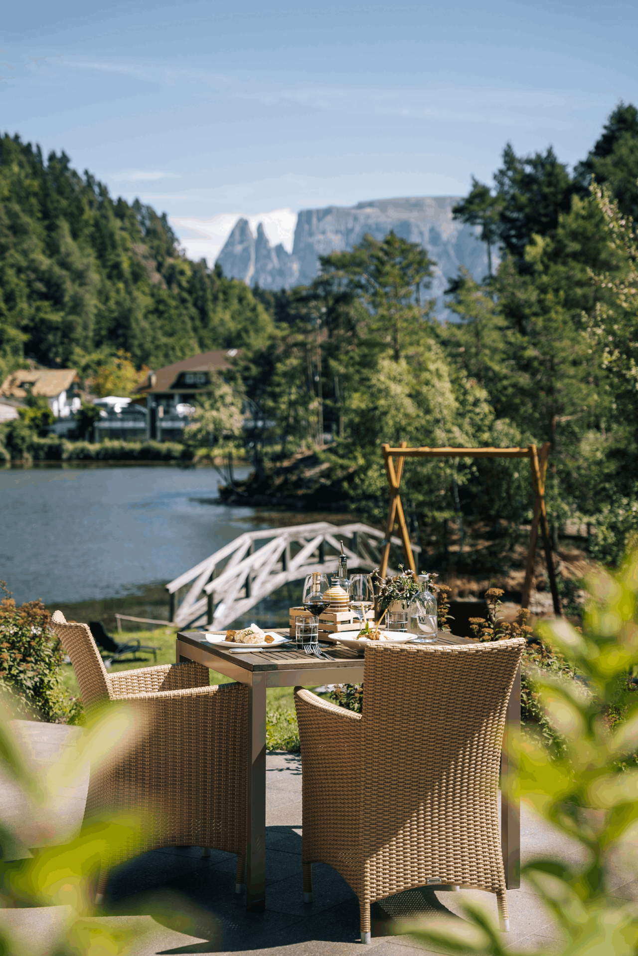 Terrasse mit einem gedeckten Tisch und Stühlen mit Blick auf einen See und die Dolomiten