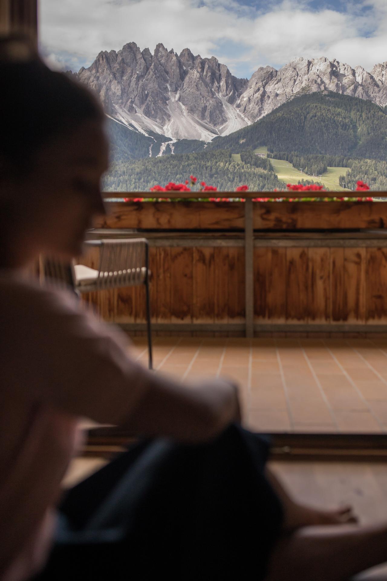 Frau, die auf einem Balkon sitzt und in die Berge schaut