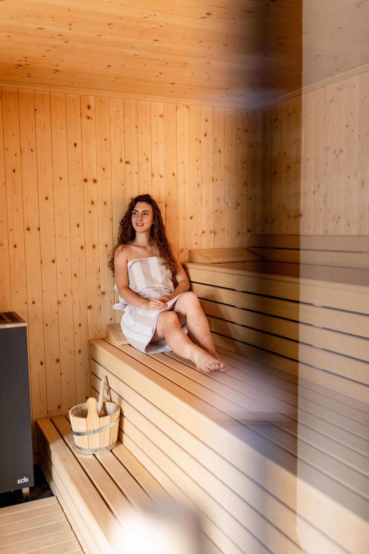Frau, die in einer kleinen Sauna sitzt