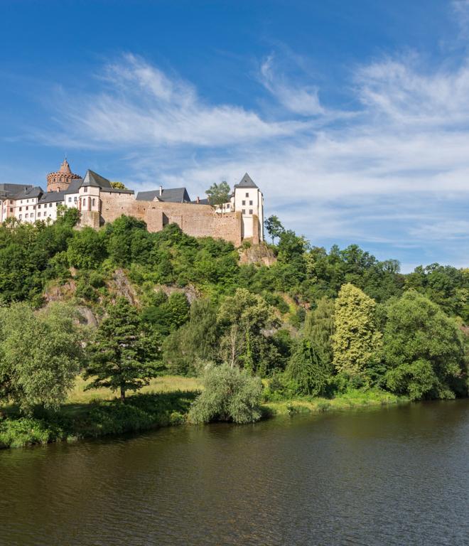 Burg auf einem waldigen Hügel an einem Fluss Ufer.