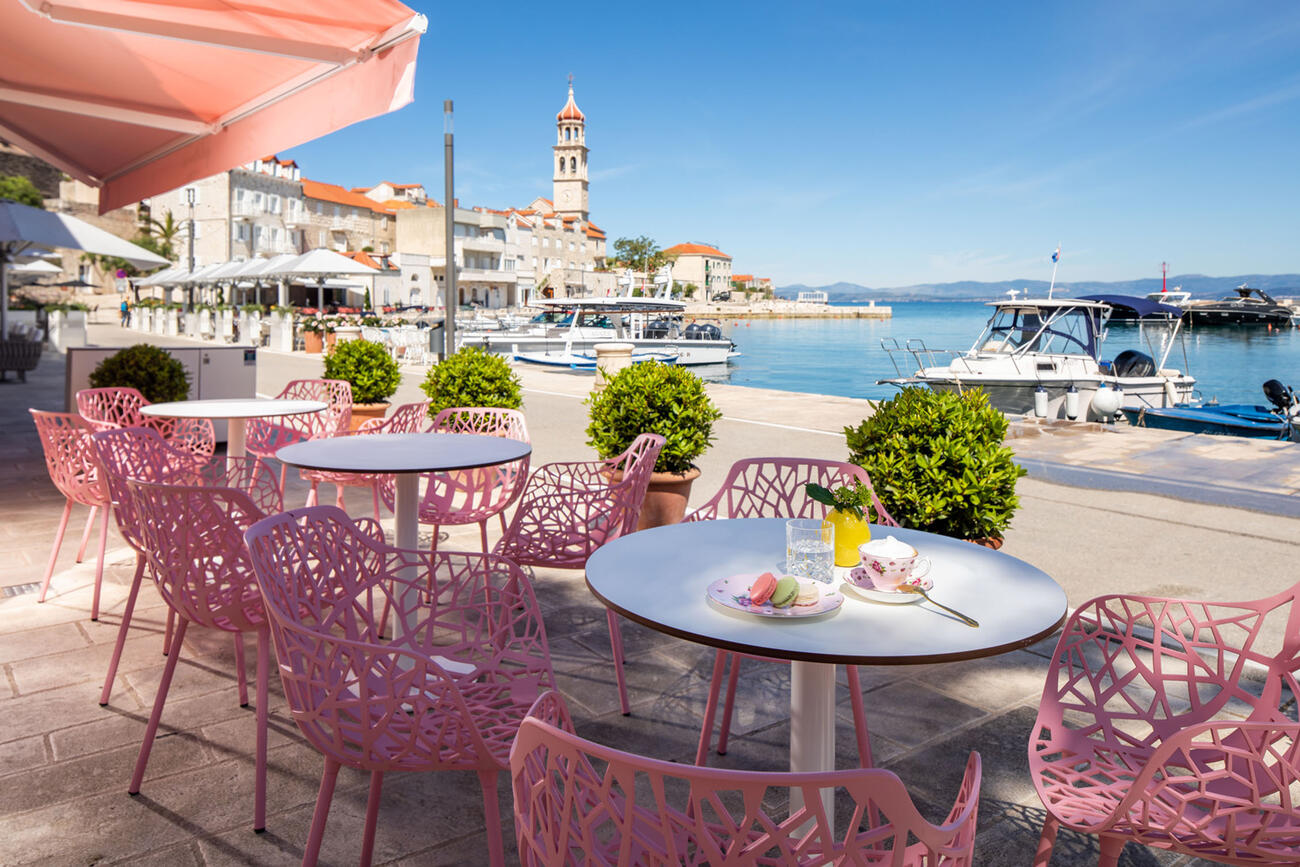 Kleine Gelateria mit rosa Stühlen und Hafenblick.