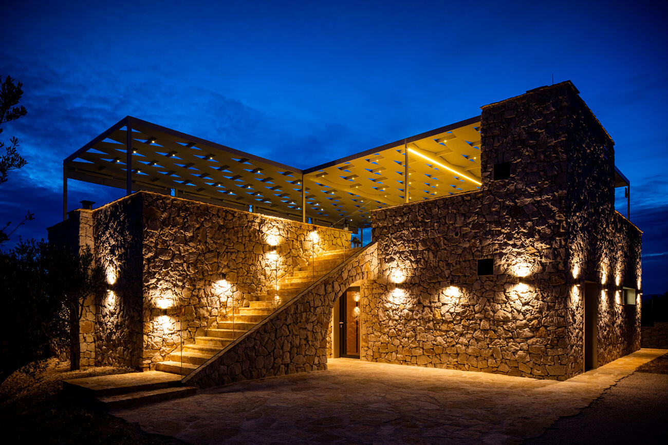 Steinernes mediterranes Haus mit beleuchteter Treppe in der Nacht.