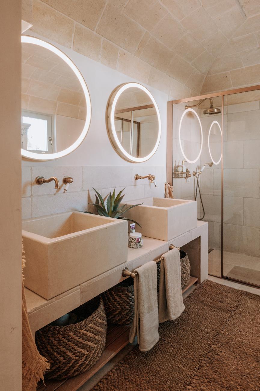 Bad mit runden beleuchteten Spiegeln und mehreren Waschbecken