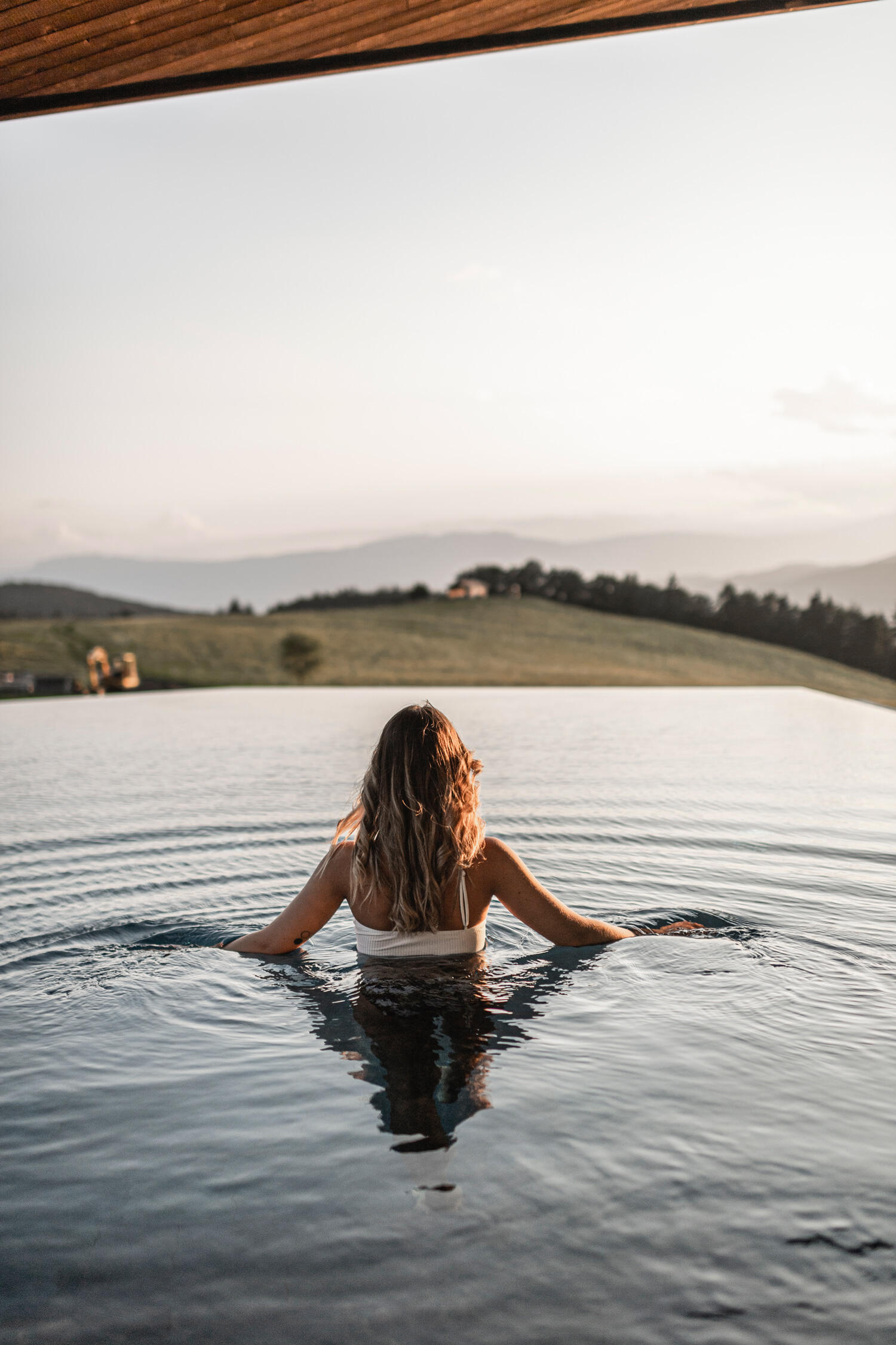 Blick auf Frau im Infinity Pool mit Aussicht auf Hügel im AEON Hotel in Südtirol