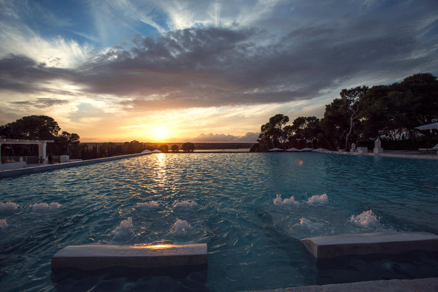 Großer Pool im Sonnenuntergang im Luxusresort Baglioni Masseria Muzza