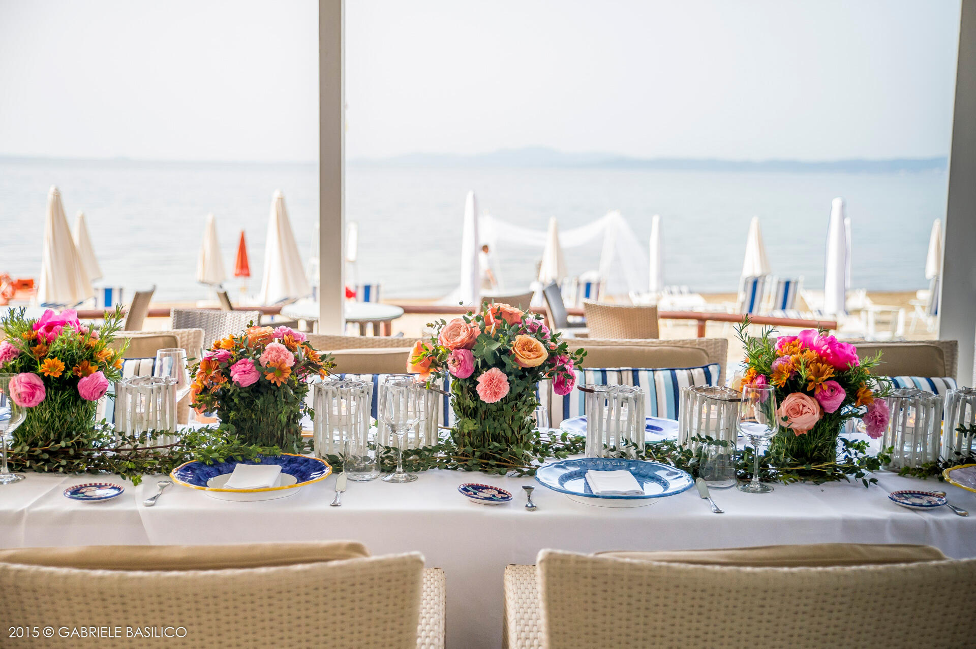 Gedeckter länglicher Tisch mit Blumensträußen und Blick auf den Strand