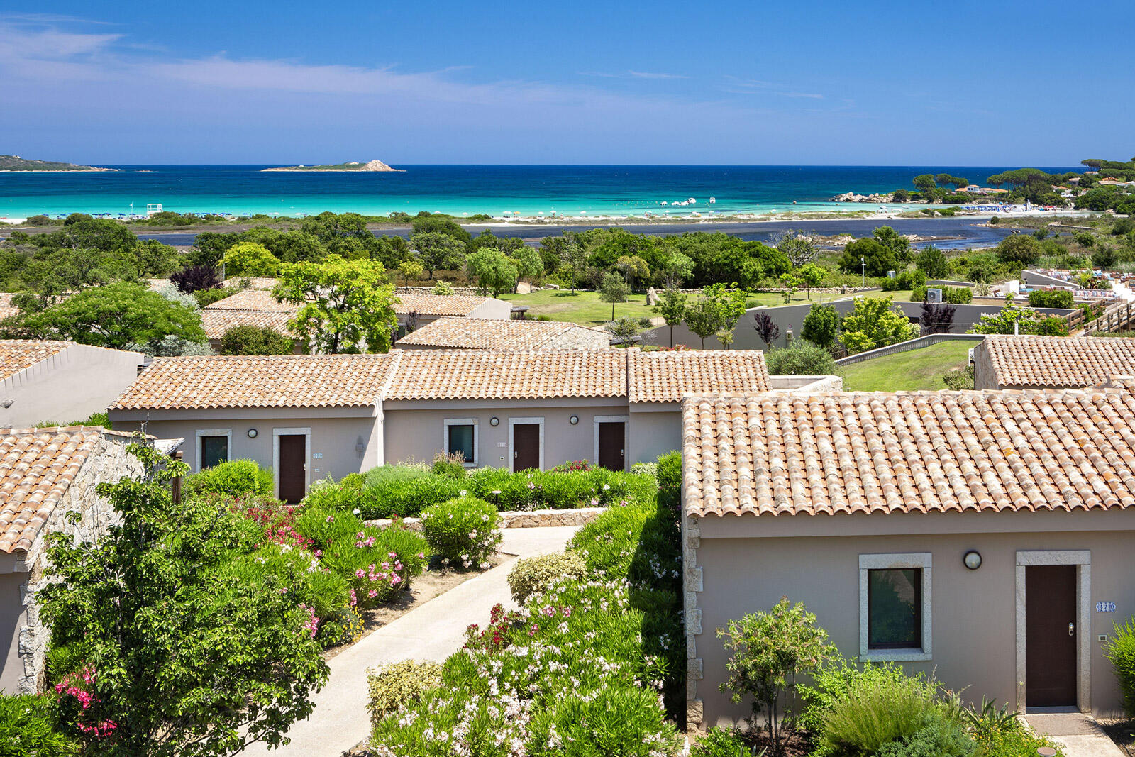Kleine Villas zwischen grünen Büschen direkt am Strand im Baglioni Resort Sardinia