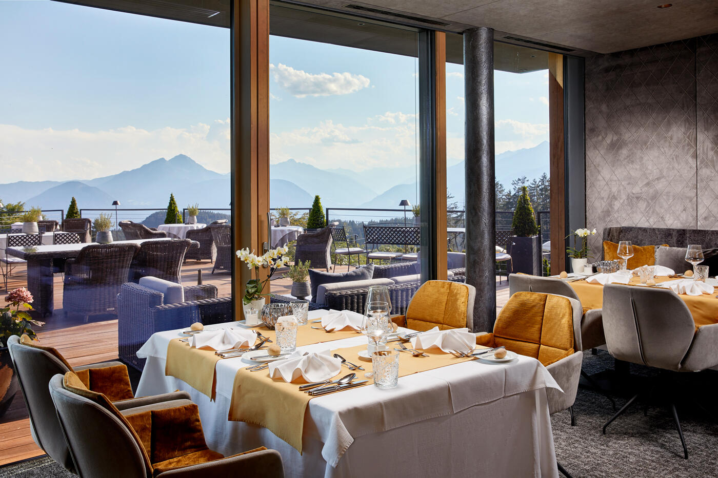 Restaurant mit großen tischen und einer Terrasse. Im Hintergrund sind die Berge