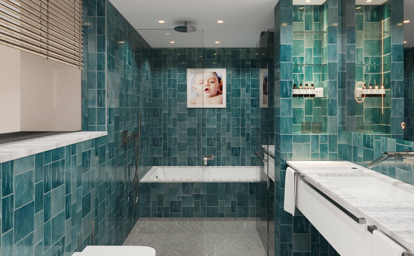 Badezimmer mit grünen Kacheln und weißen Becken und Badewanne. An der Wand hängt ein Bild von einem Baby.