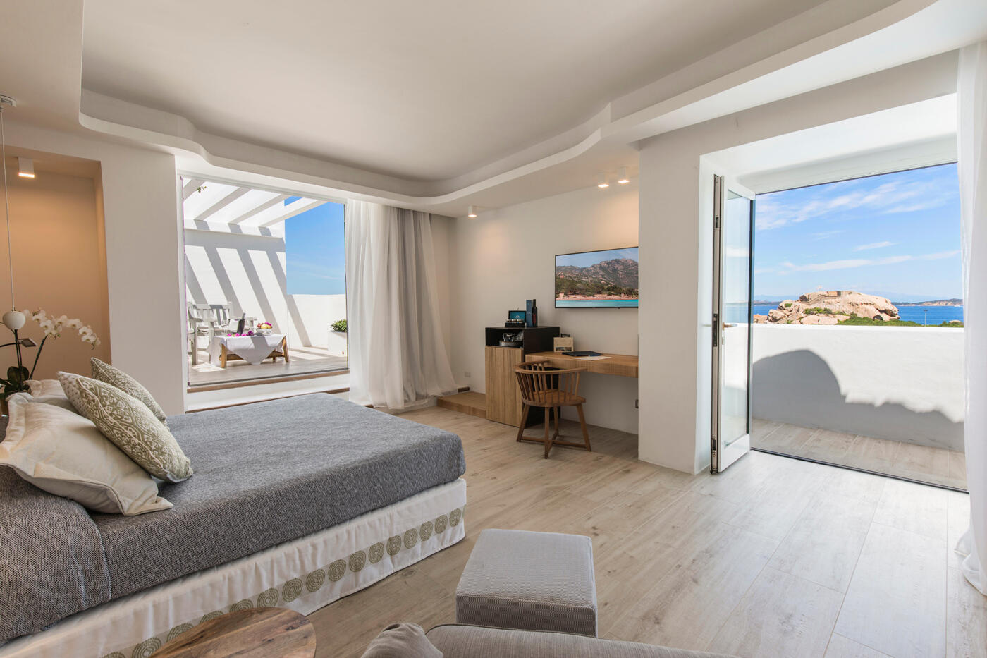 Zimmer im Grand Relais Nuraghi: Ein großes Doppelbett und zwei große Terrassentüren, die Blick auf das Meer geben.