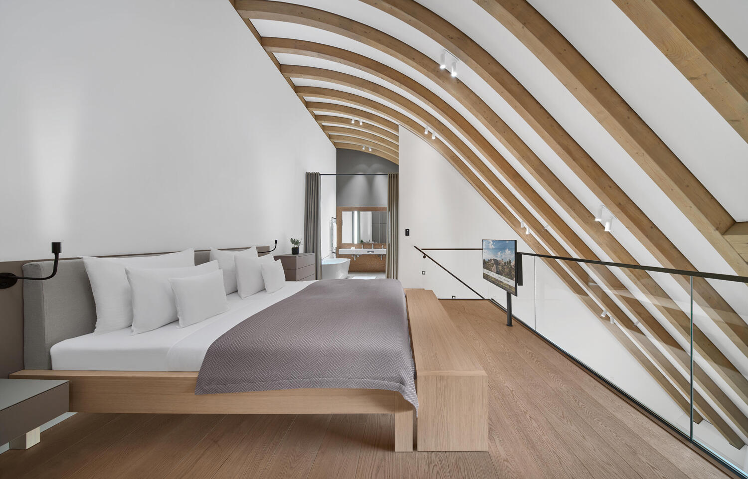 Modernes schlichtes Hotelzimmer mit Doppelbett und Holzbiden, an der Decke sind Holzbalcken