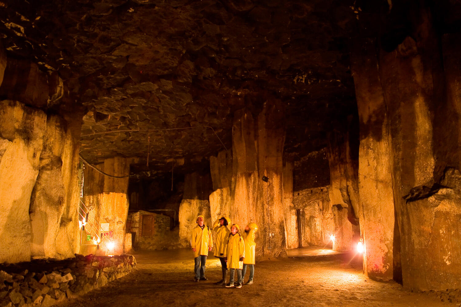 Beleuchteter Lavakeller im Vulkanpark Osteifel: Familie mit gelben Jacken bewundert die Gesteine.