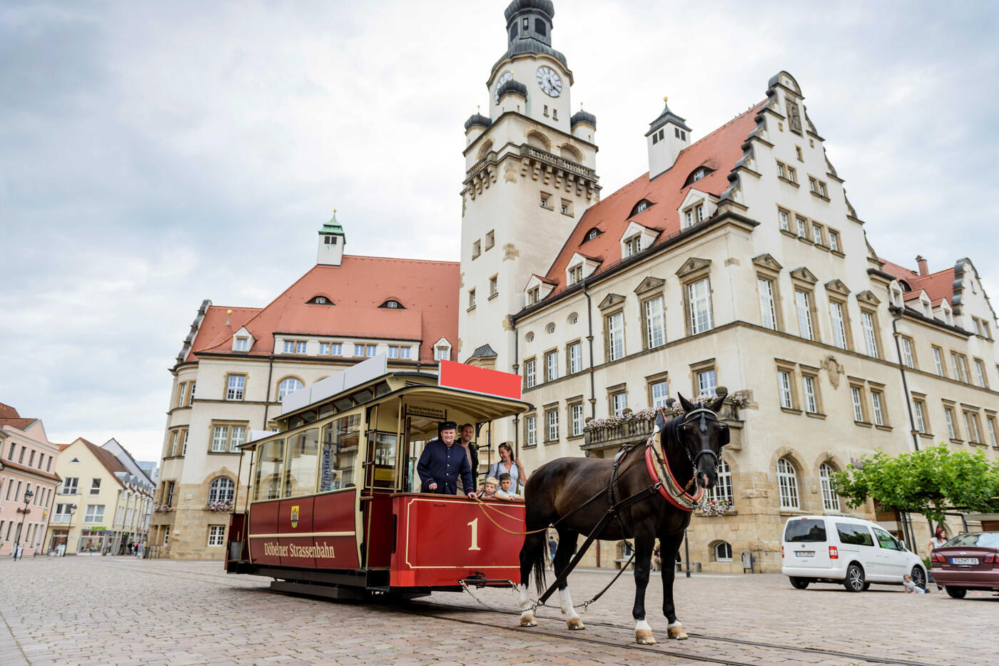 Pferd, dass an eine Pferdestraßenbahn gebunden ist in einer Altstadt.