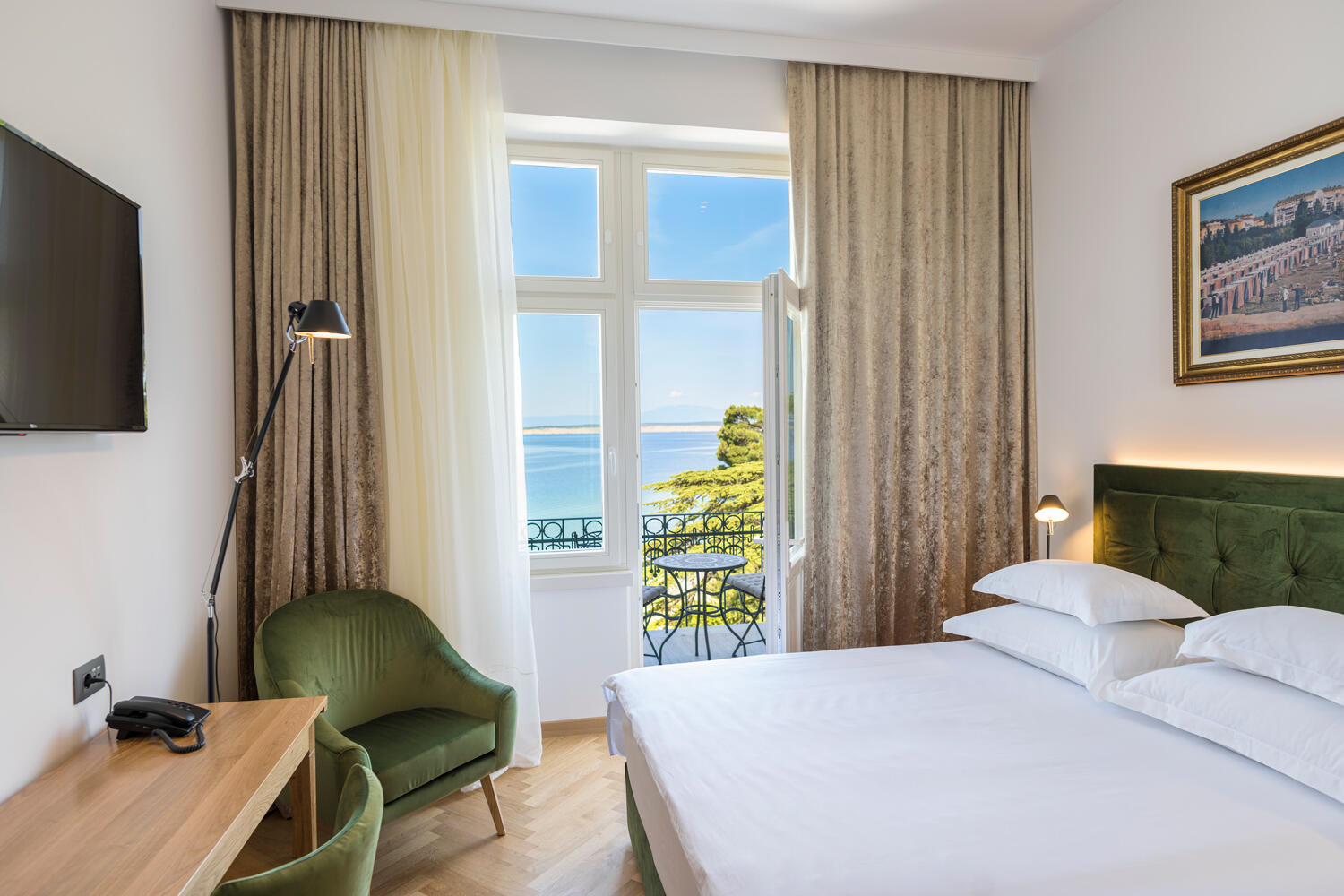 Innenansicht auf Hotelzimmer mit Bett und Balkon mit Aussicht auf das Meer