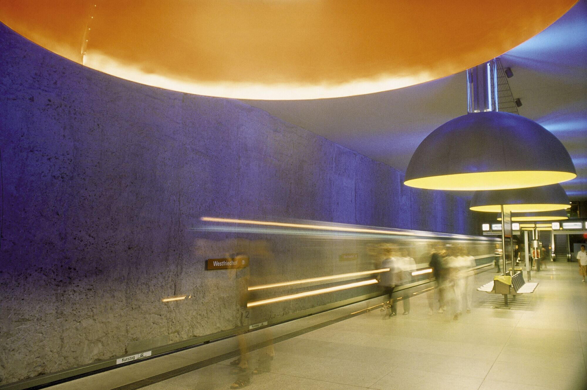 U-Bahn Station in München mit Blick auf Lampeninstallationen von Ingo Maurer und Menschen in Bewegung im Hintergrund