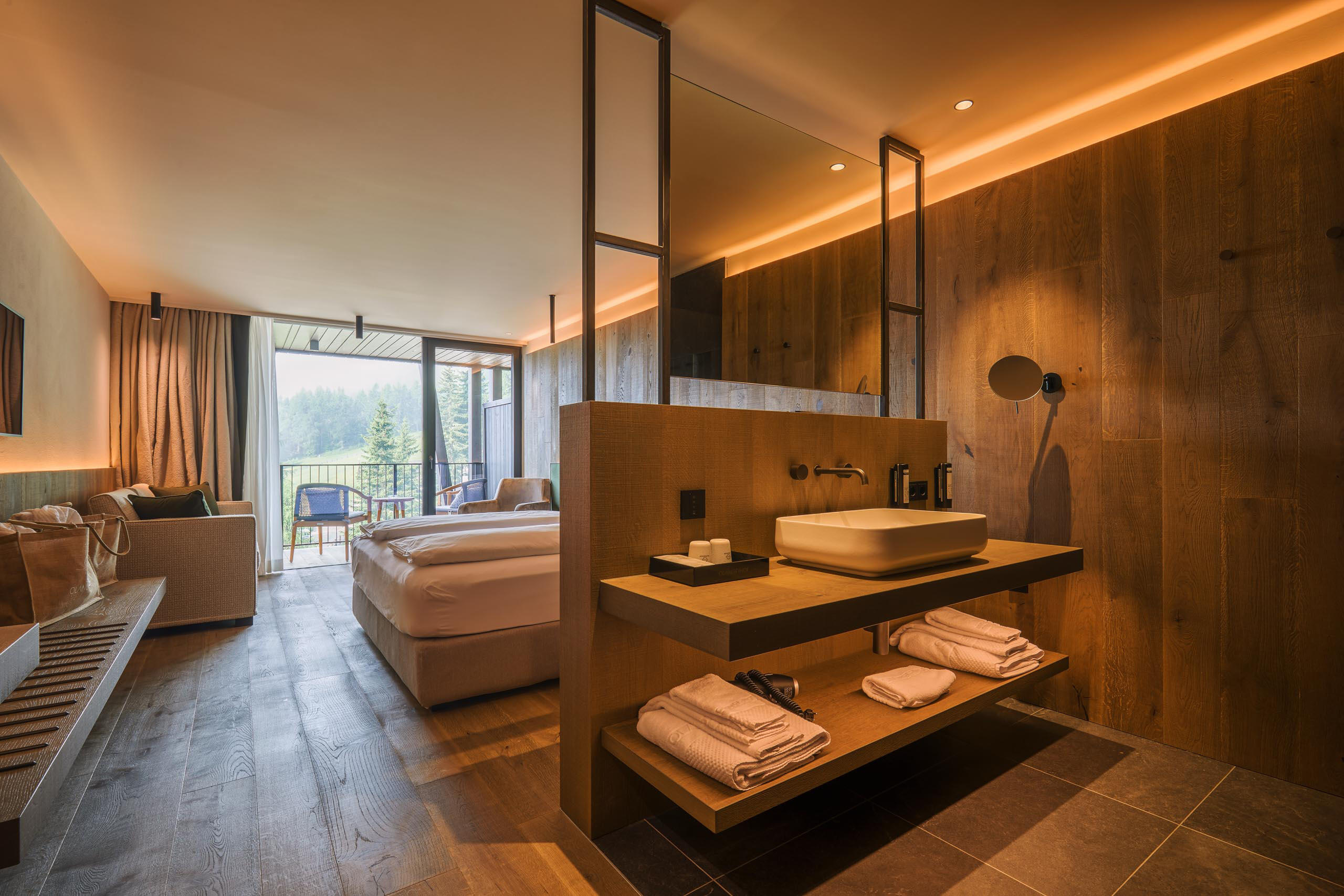 Hotelzimmer mit Holzwänden, großem Doppelbett und modernem Waschbecken.
