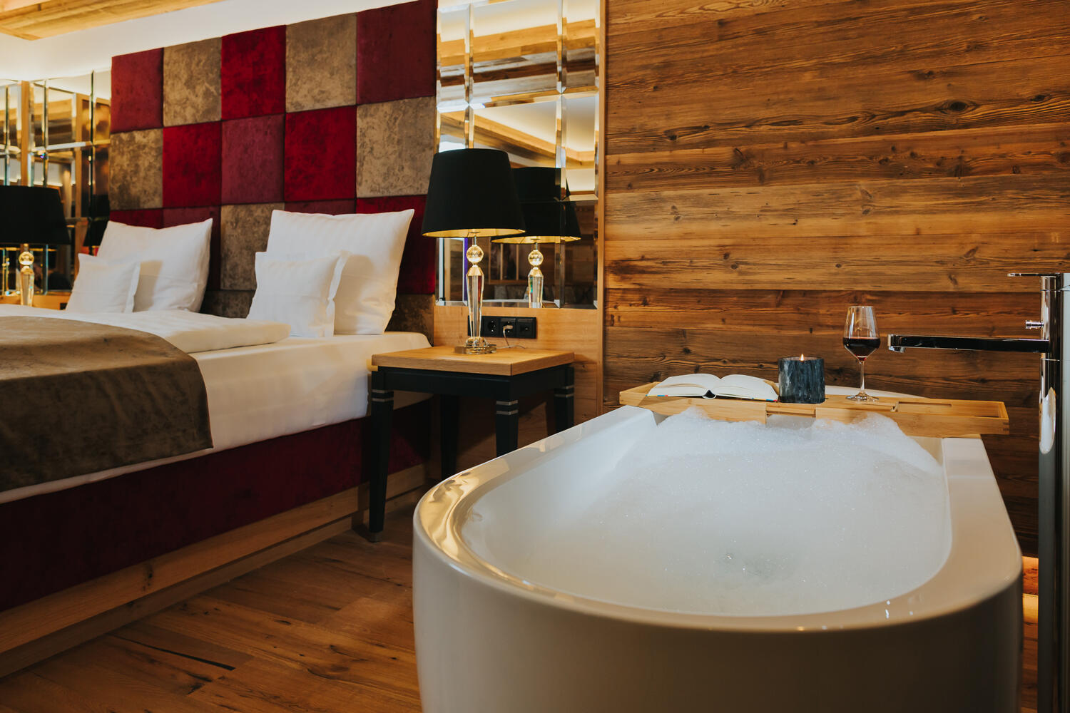 Hotelschlafzimmer aus Holz mit Badewanne direkt neben dem Bett
