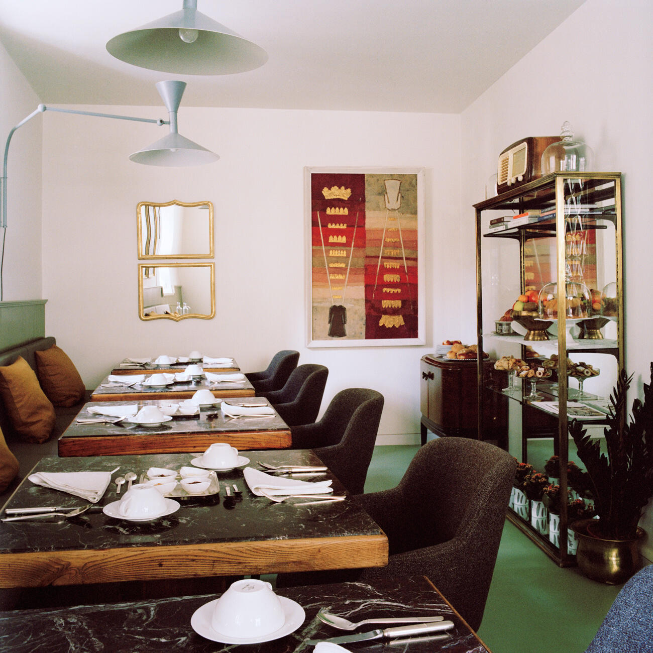 Bistro Innenansicht mit gedeckten Tischen, Stühlen und grünem Boden im Steinach Townhouse Meran