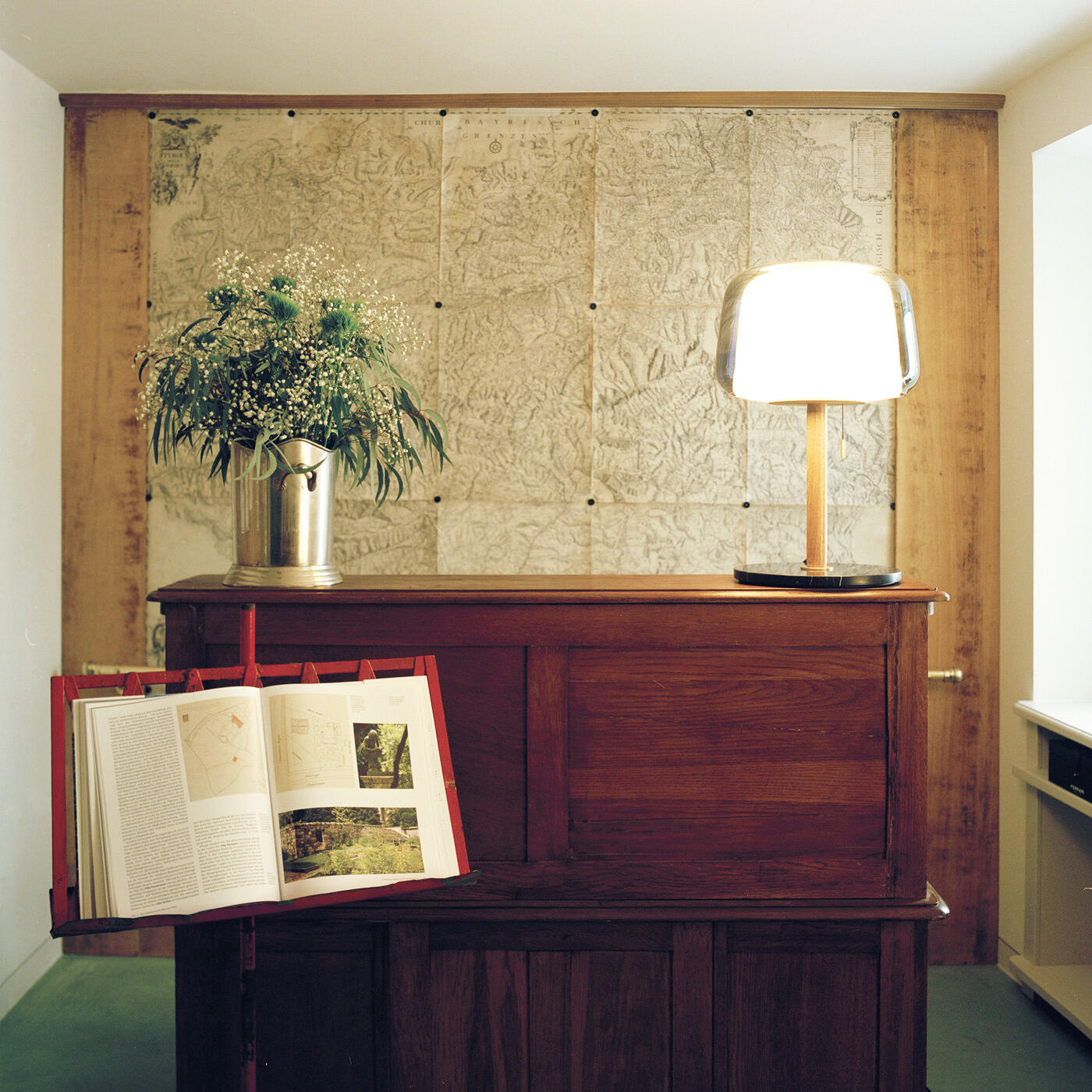 Hotelrezeption im antiken Design mit Holzpult, Blumenstrauß und Lampe im Steinach Townhouse Meran