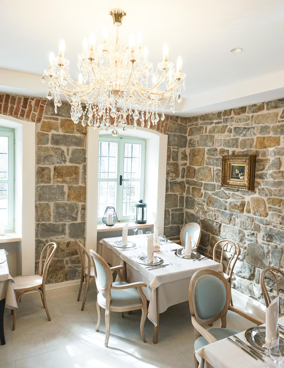 Blick auf gedeckten Tisch in einem rustikalen Restaurant mit Kronleuchter und Steinwänden in der Villa Majda