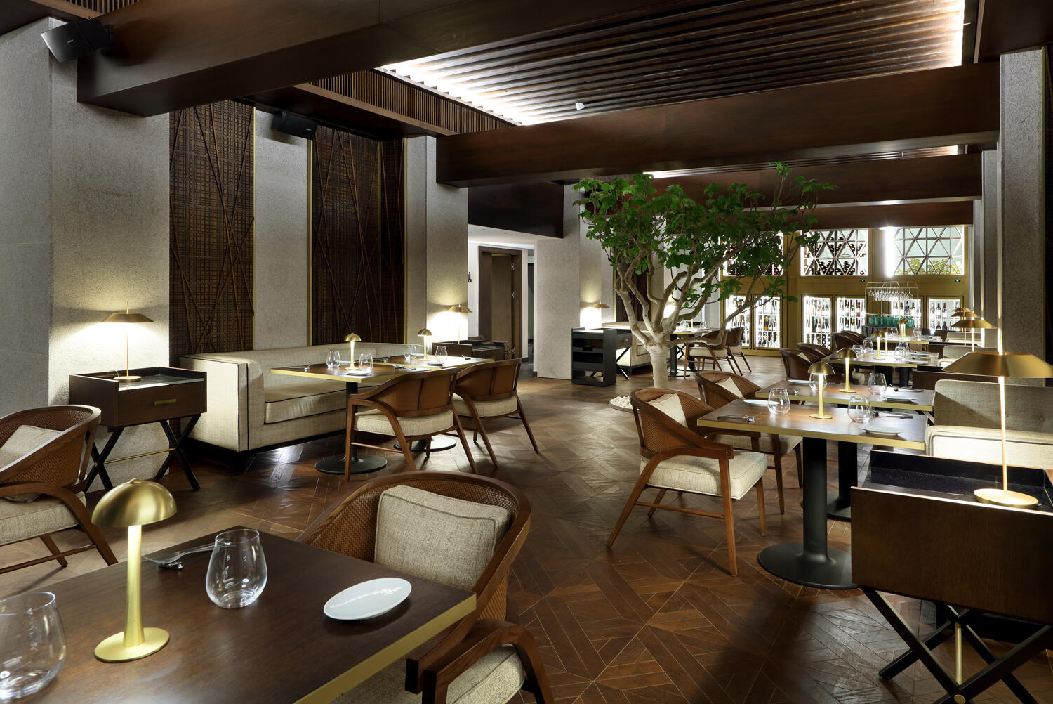 Restaurant mit dunkelbraunen Boden und Möbek und einem Olivenbraum im Bless Hotel Ibiza.
