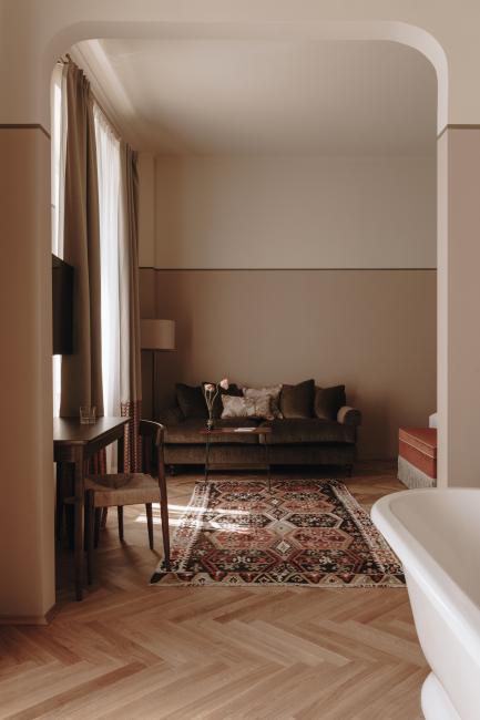 Blick auf einen Raum mit freistehender Wanne, Couch und Teppich