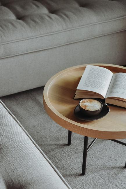 Kleiner runder Wohnzimmertisch mit einem offenen Buch und einer schwarzen Tasse Kaffee
