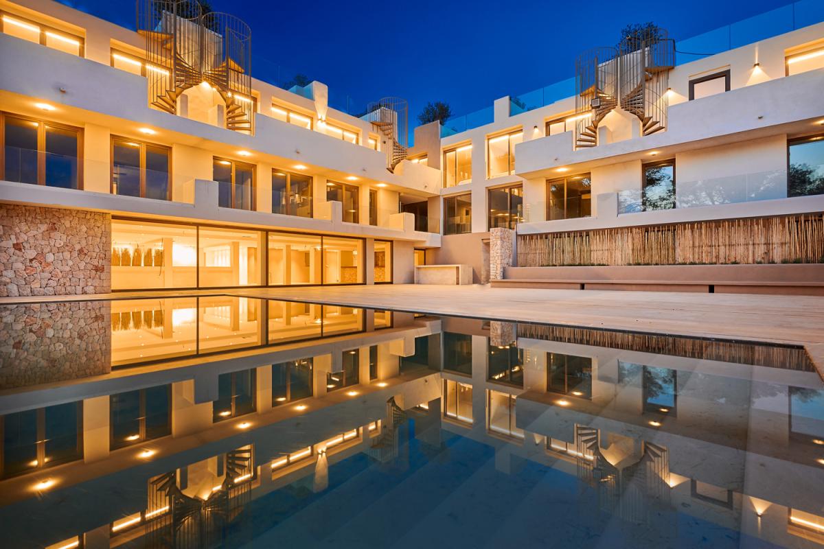 Barefoot Hotel Mallorca Aussenansicht: Pool in Abendstimmung, in dem sich das Hotel spiegelt. Drumherum die weiße Hotelfassade mit Balkonen.
